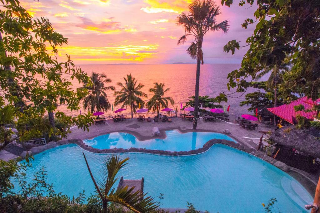 马比尼鹰角海滩潜水度假酒店的海滩上的游泳池,背景是日落