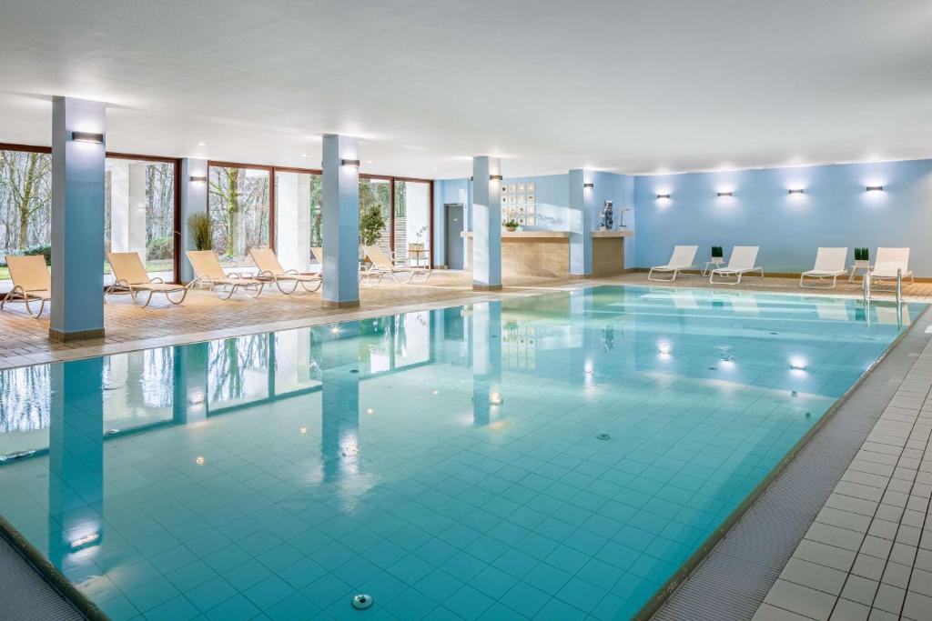 卢森堡卢森堡希尔顿逸林酒店的一座配有桌椅的酒店游泳池