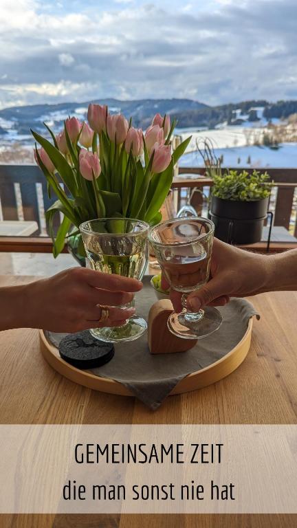 米森-维尔哈姆斯Ferienwohnung Alpenflair mit Pool und Sauna & direkt am Skilift的桌子上摆放着两杯眼镜和鲜花的桌子