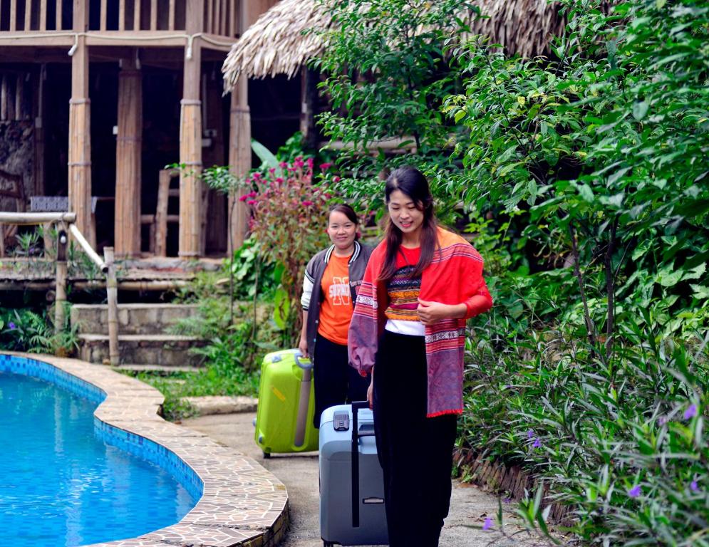 和平Duân Thảo homestay的两名携带行李的女士站在游泳池旁