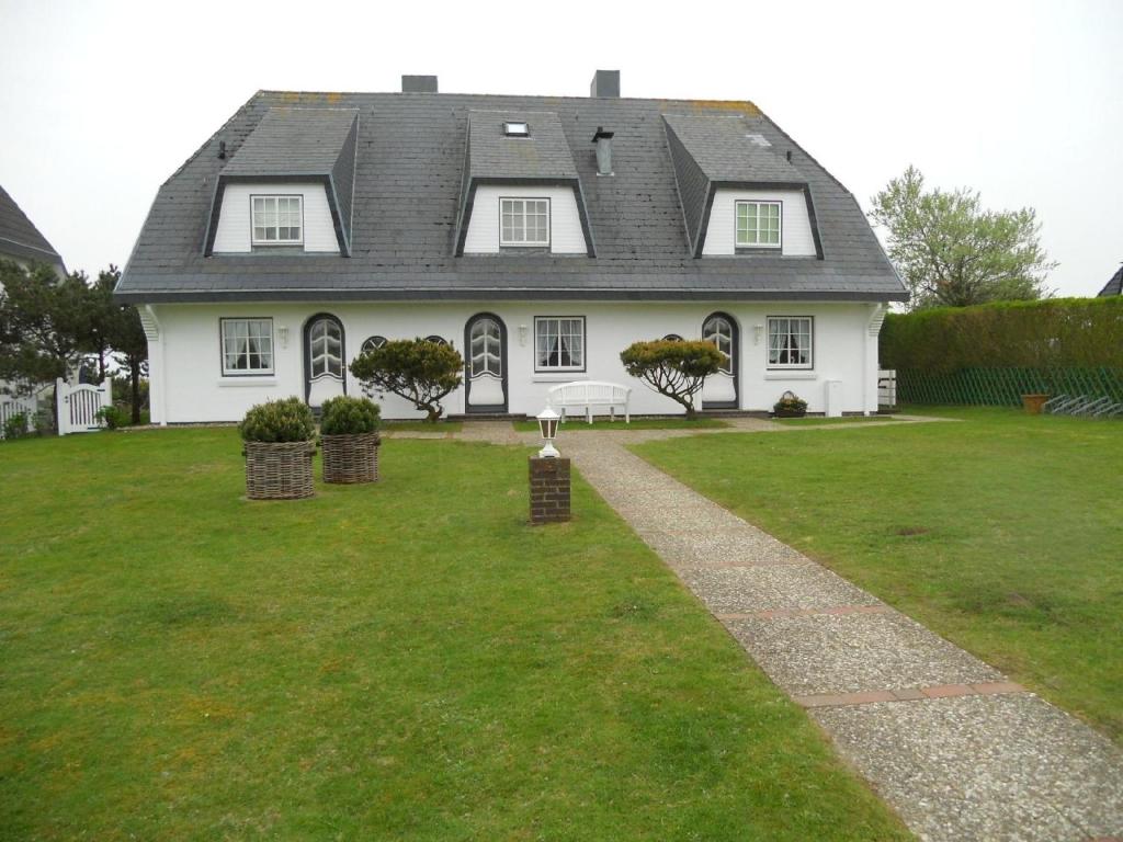 曼克玛肖Ferienwohnung für 2 Personen ca 55 qm in Munkmarsch, Nordfriesische Inseln Sylt的一座带绿色庭院的大型白色房屋