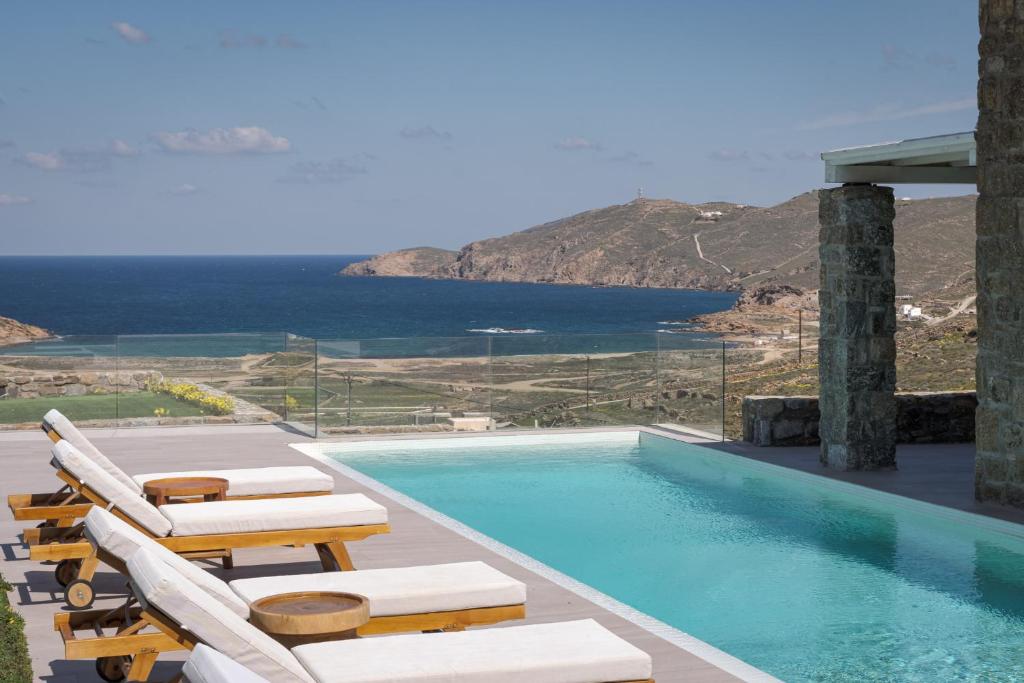 米克诺斯城Retreat Hill Luxury Villas Mykonos的一个带椅子的游泳池,享有海景