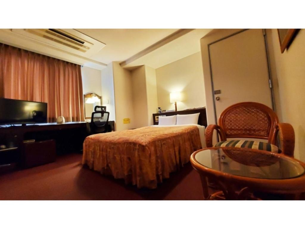 延冈市Nobeoka Urban-Hotel - Vacation STAY 30459v的酒店客房,配有一张床、一张桌子和椅子