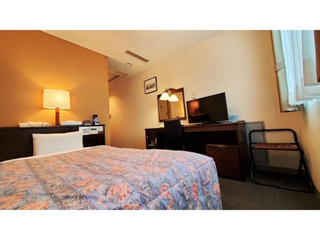 延冈市Nobeoka Urban-Hotel - Vacation STAY 30463v的酒店客房配有一张床、一张书桌和一台电视。