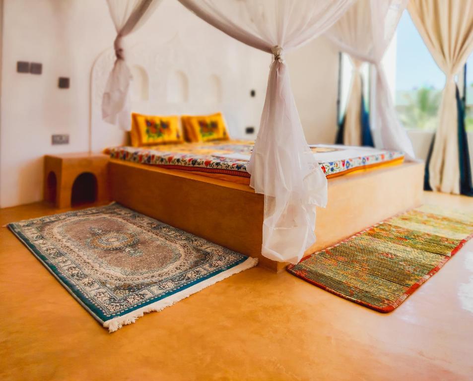 瓦塔穆Casa Maridadi的卧室配有两张床,地板上铺有2个地毯。