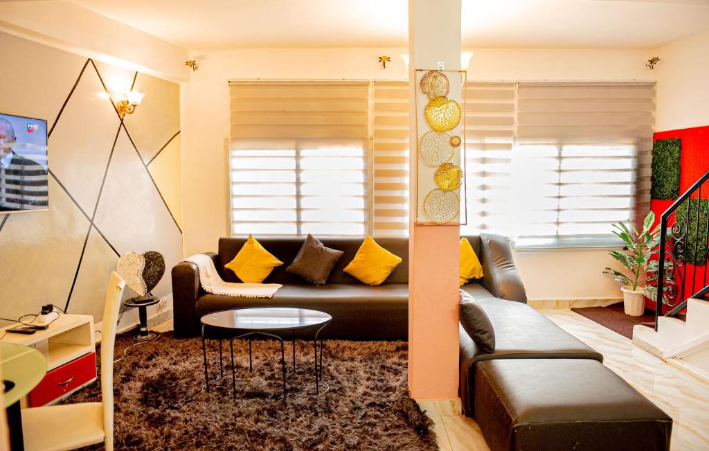 雅温得Appartement chic et spacieux près centre Yaoundé的客厅配有真皮沙发和黄色枕头。