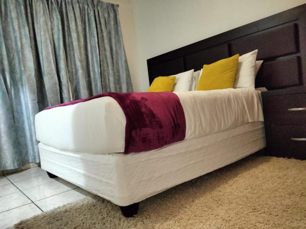 姆巴巴内Apartment on MR103的一间卧室配有带白色和黄色枕头的床