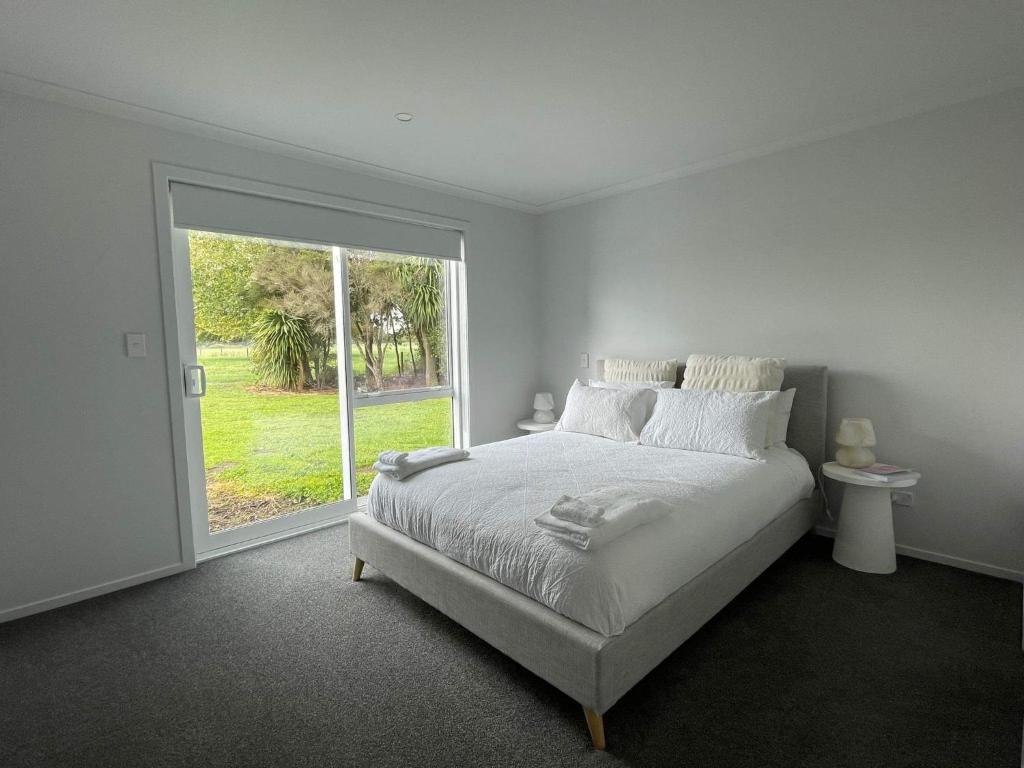 TaupiriModern and new house的白色的卧室设有床和大窗户