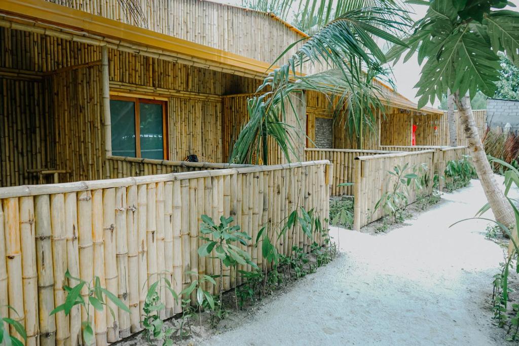 ThinadhooEcoboo Maldives的一座带围栏和棕榈树的木屋