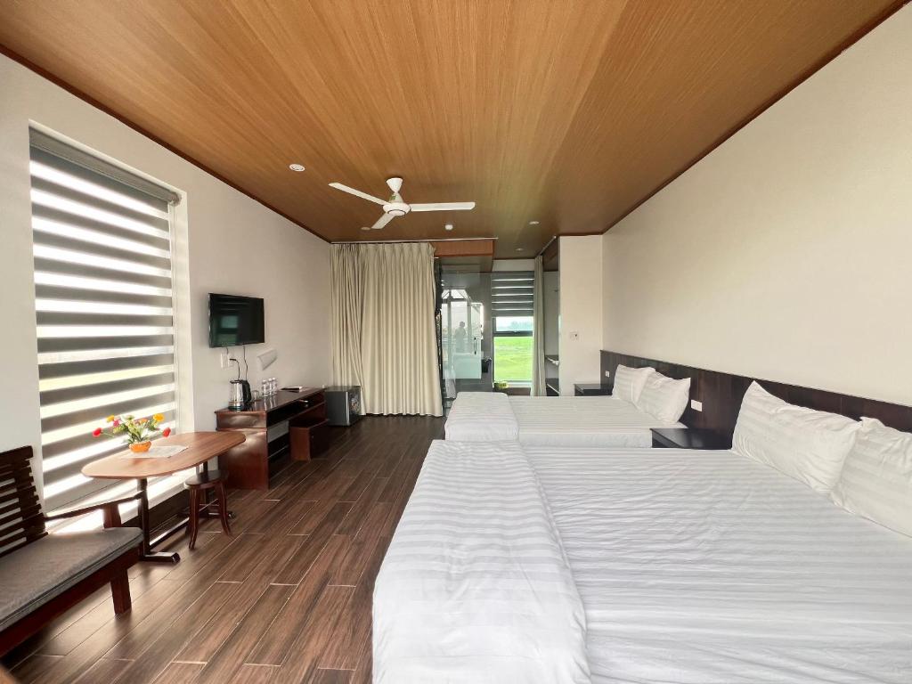 Cẩm XuyênHOMESTAY THIÊN CÂM的酒店客房设有两张床和一张桌子。