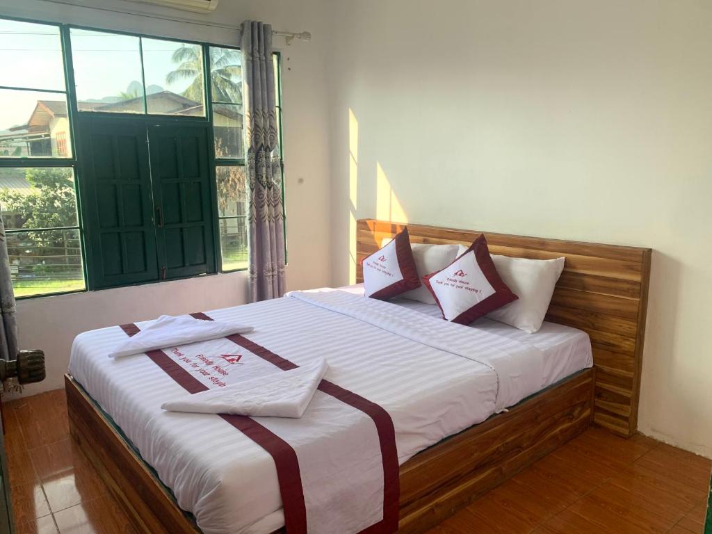 万荣Vang Vieng Lily Guesthouse的一间卧室配有一张带红色和白色枕头的大床