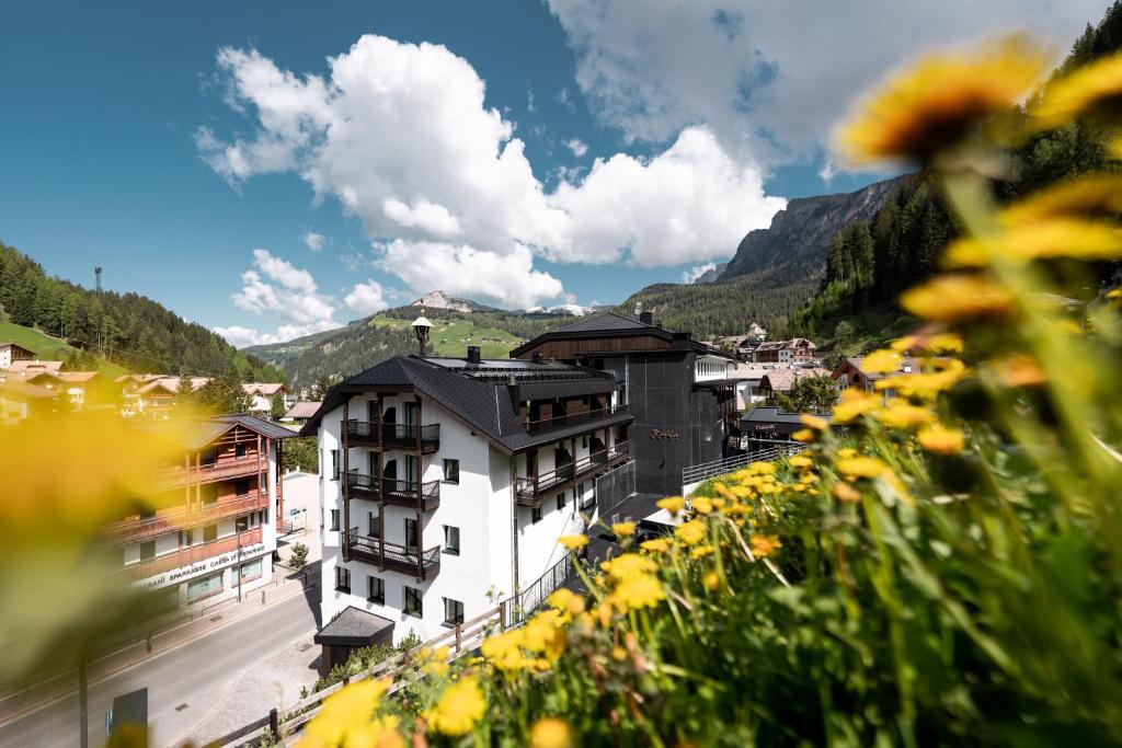 塞尔瓦迪加尔代纳山谷Stella Hotel - My Dolomites Experience的享有山脉小镇的黄色鲜花美景