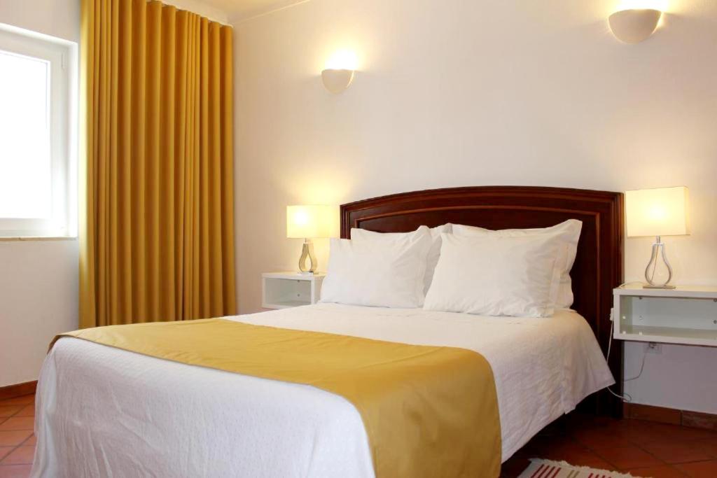 米尔芳提斯城Guest House - Duna Parque Group的一间卧室配有一张带黄色窗帘的大床