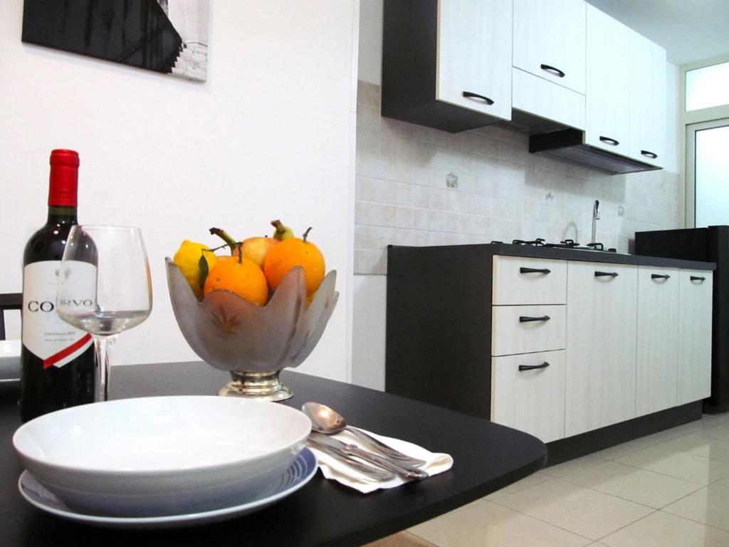 科米索Trinacria House - Appartamento Deluxe Comiso的一张桌子,上面放着一碗水果和一瓶葡萄酒