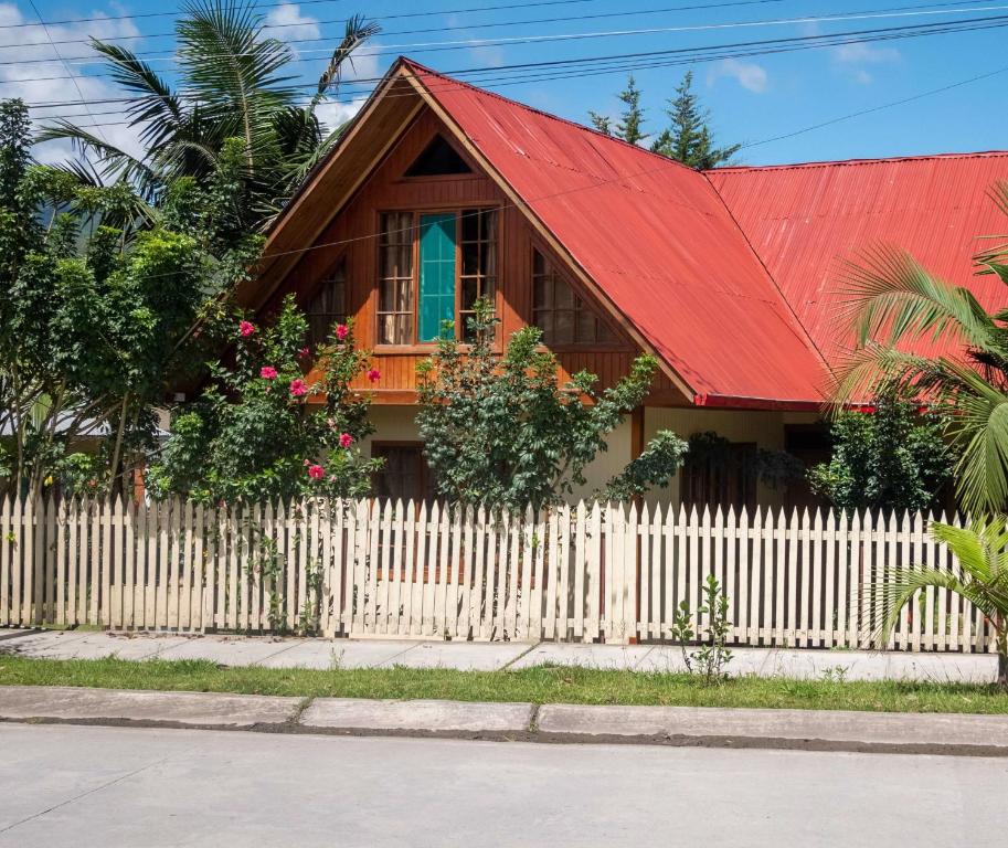 奥克萨潘帕Hospedaje Cattleya的一座红色屋顶和白色围栏的房子