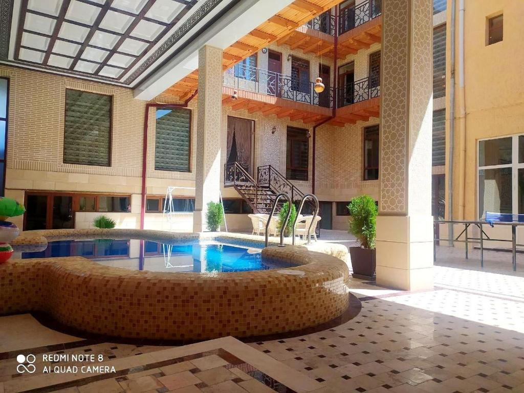 布哈拉Hotel Shams的一座大建筑,在庭院里设有一个游泳池