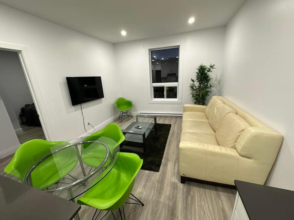 蒙特利尔Appartement 2 chambres - 202的客厅配有白色沙发和绿色椅子