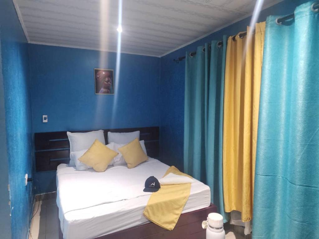 MpongweBukari Executive Lodge的一间卧室配有一张蓝色墙壁和黄色窗帘的床