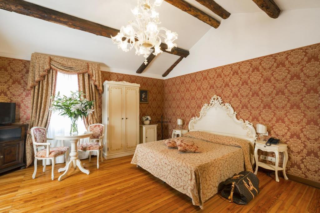 威尼斯帕拉索瓜迪酒店的一间卧室配有一张床、一张桌子和一个吊灯。
