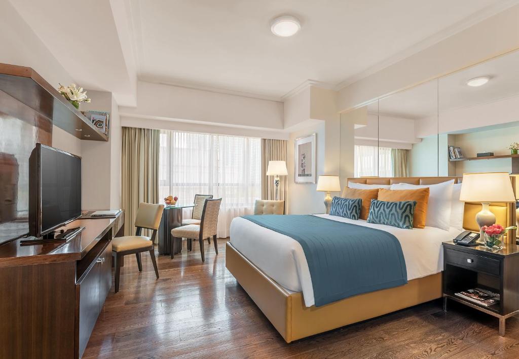 马尼拉Aruga Apartments by Rockwell Makati的酒店客房,配有床和电视