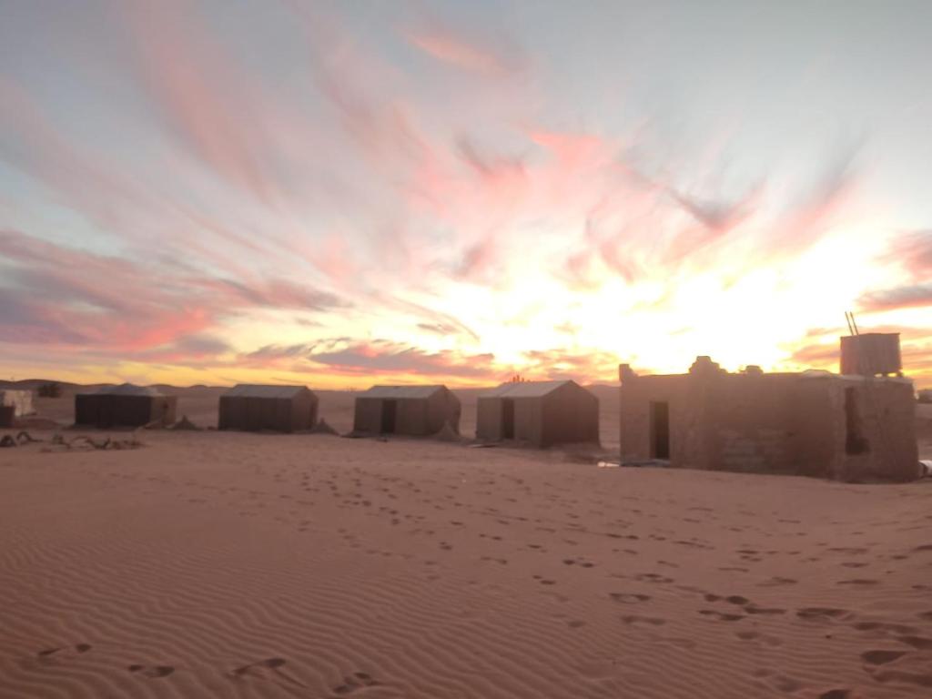 MhamidWüstencamp in Erg Chegaga的沙漠中的日落,沙中建筑