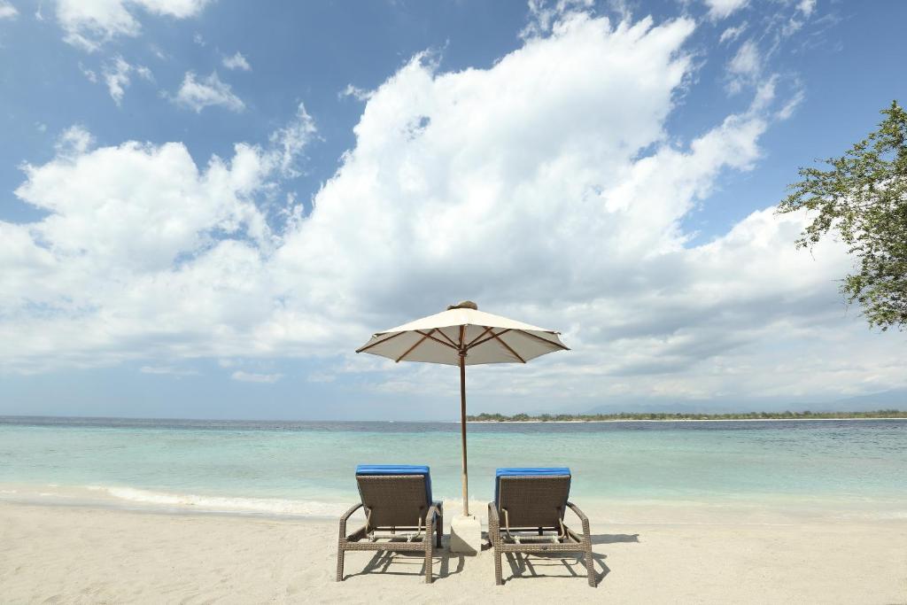 吉利特拉旺安Vamana Resort - CHSE Certified的海滩上的两把椅子和一把遮阳伞