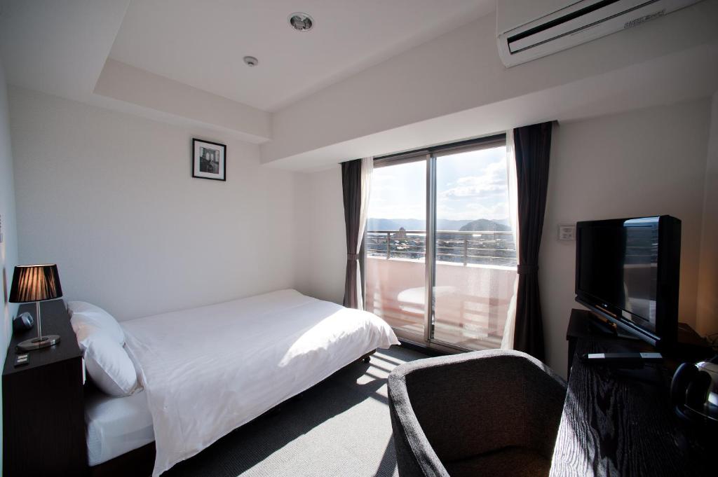 大村市Omura Station Hotel的酒店客房设有一张床和一个大窗户