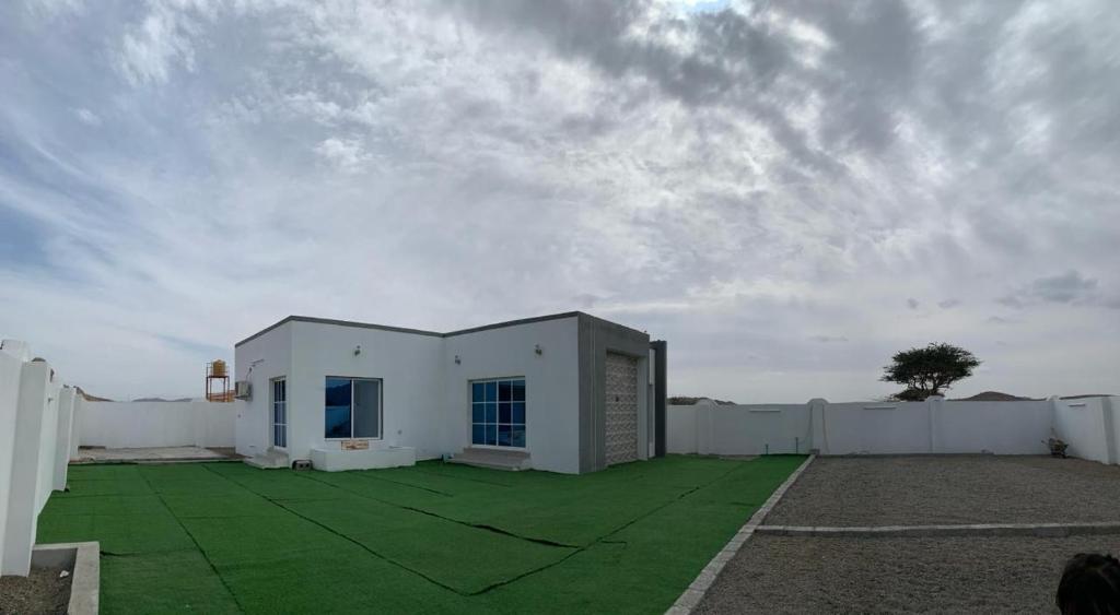 Ibrāبيت الضيافه للتواصل:98423336的前面有绿色草坪的白色建筑