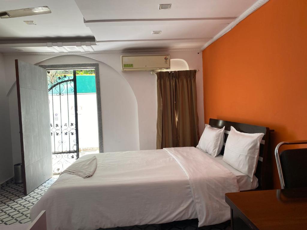 浦那Relaxing 3 Ac Room Near Pune Airport Kalyani Nagar的一间卧室配有一张橙色墙壁的床