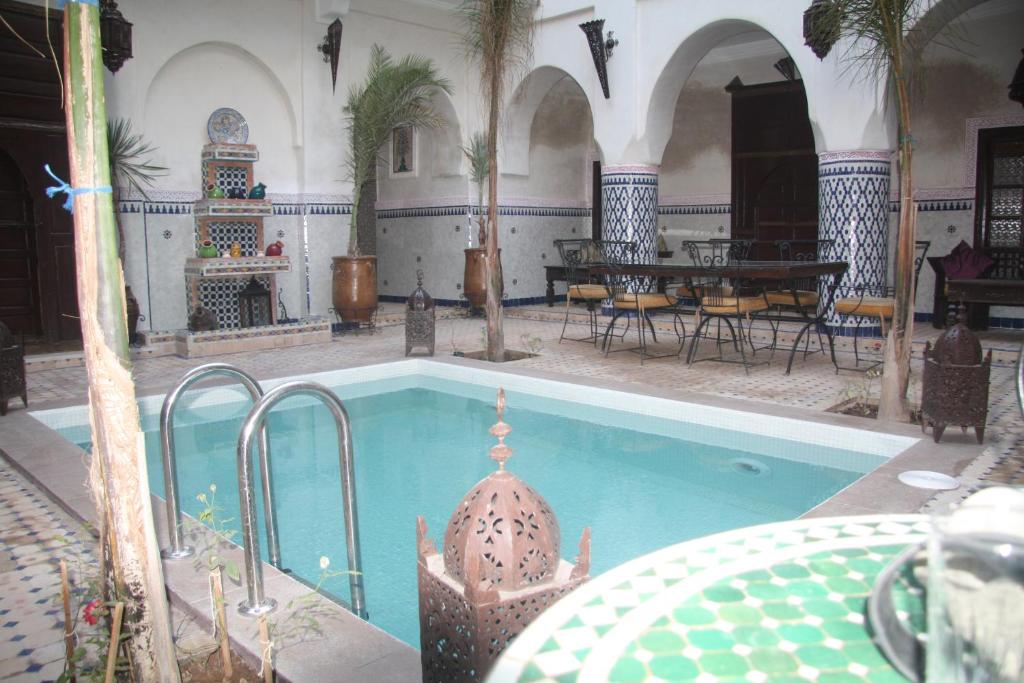 马拉喀什达尔穆莱阿里摩洛哥传统庭院旅馆的一座带桌椅的游泳池