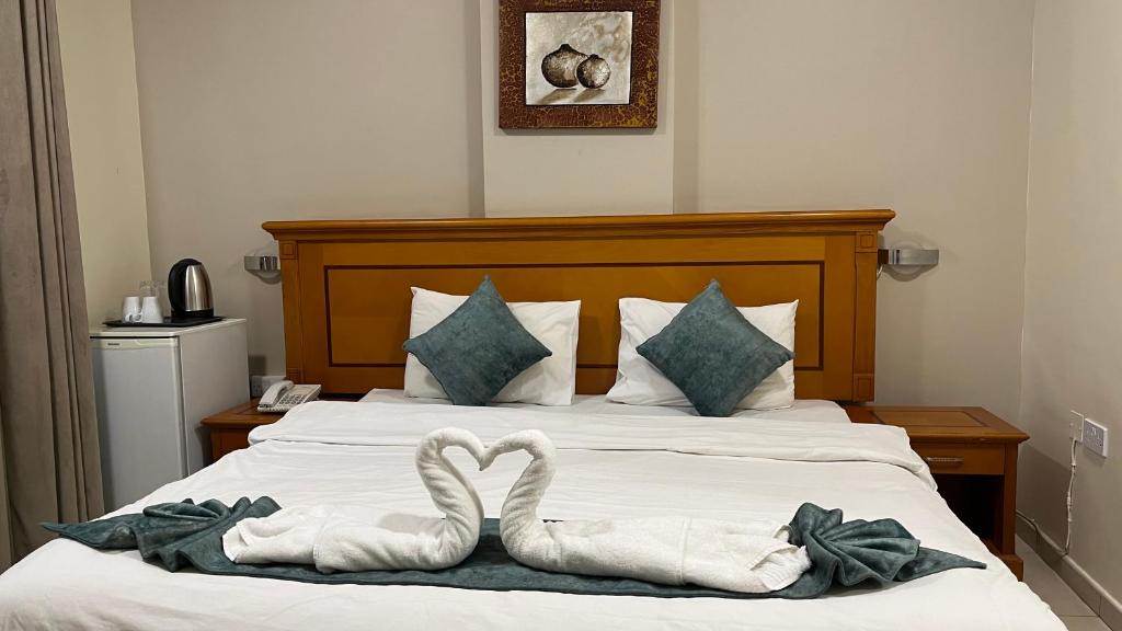 马斯喀特Al Murooj Hotel Apartments的两个天鹅躺在床上