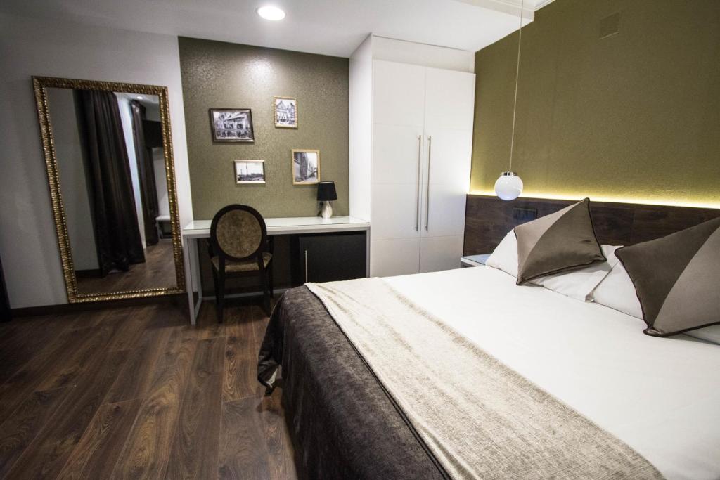 巴塞罗那现代酒店的一间卧室配有一张床、一张书桌和一面镜子