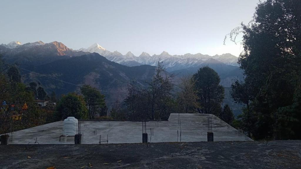 MunsyariComet Himalayan Paradise Homestay, Munsiyari的山丘上的建筑,背景是山脉