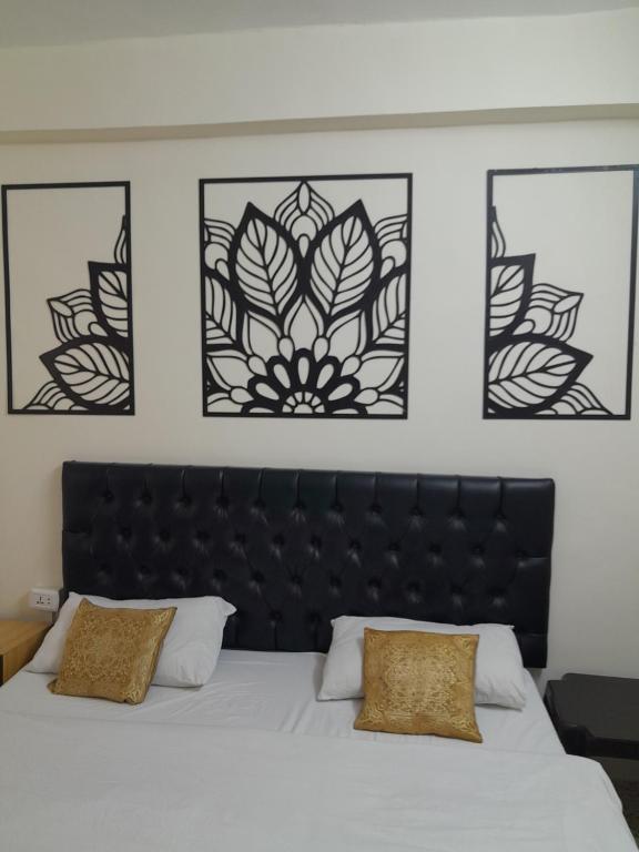 安曼哈穆达酒店的一间卧室配有黑色床头板和三幅框图
