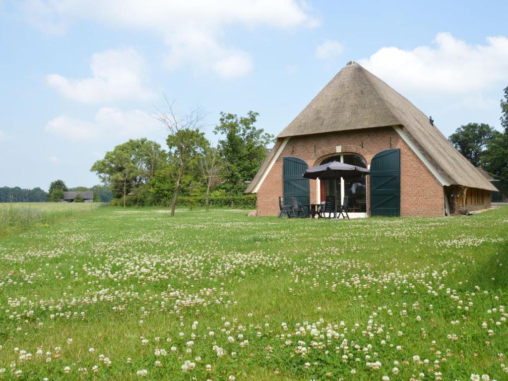 GeesterenQuaint Farmhouse in Geesteren with Meadow View的花田中茅草屋顶小屋