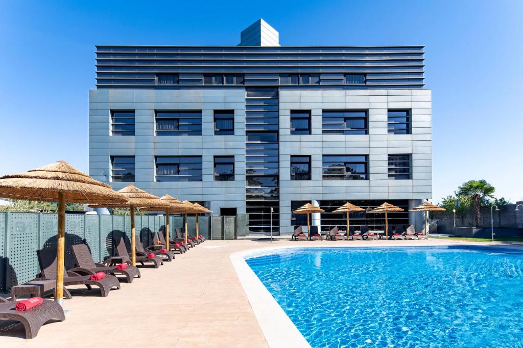 马德里纽沃波斯顿酒店的酒店设有带椅子和遮阳伞的游泳池