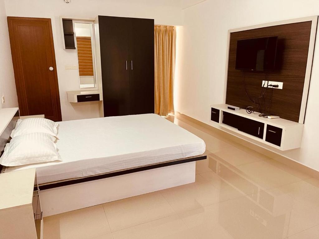 特里凡得琅Amalas Lodge的一间卧室配有一张床和一台平面电视