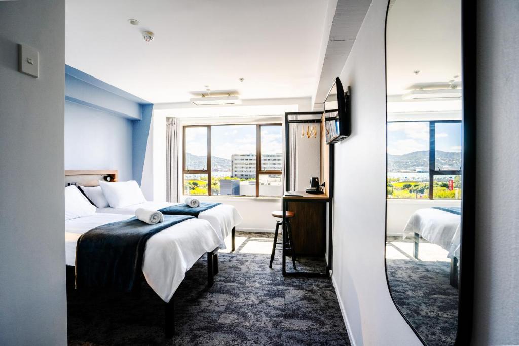 惠灵顿Haka House Wellington的酒店客房设有两张床和窗户。