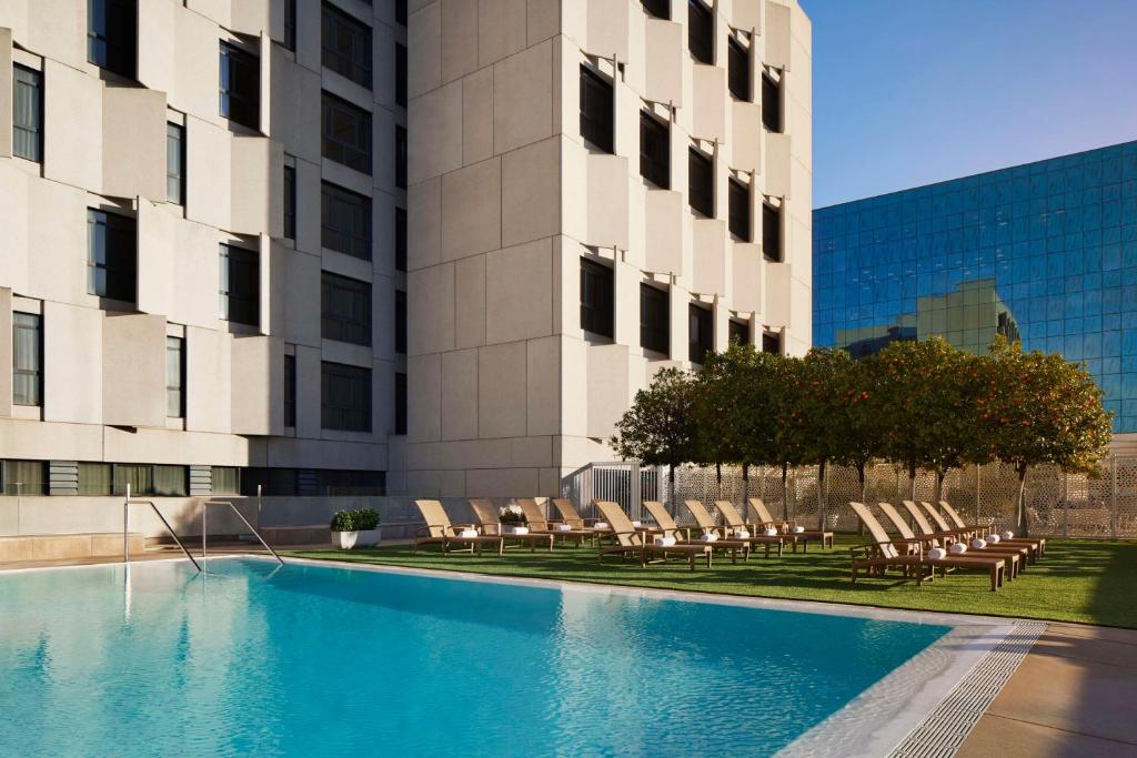 塞维利亚塞维利亚NH酒店集团的一座大楼前的游泳池,配有躺椅
