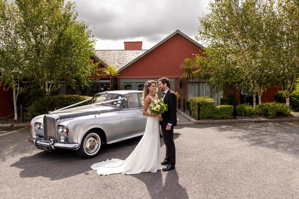 德罗赫达格兰赛德酒店的站在汽车旁的新娘和新郎