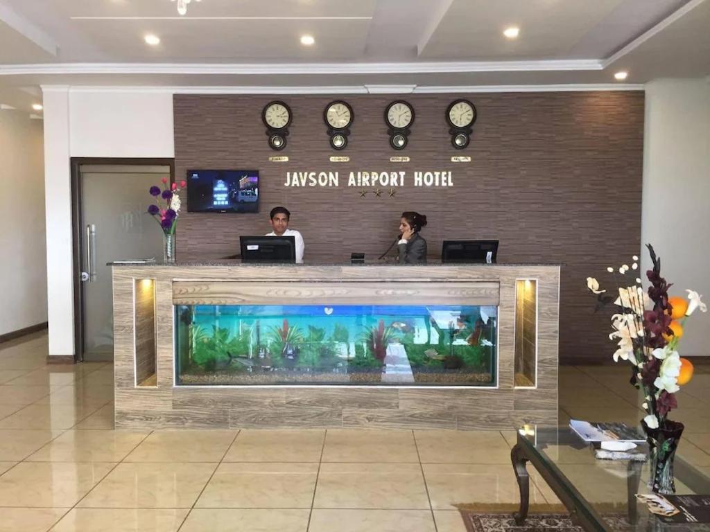 锡亚尔科特Javson Airport Hotel的两个人站在大堂的鱼缸后面