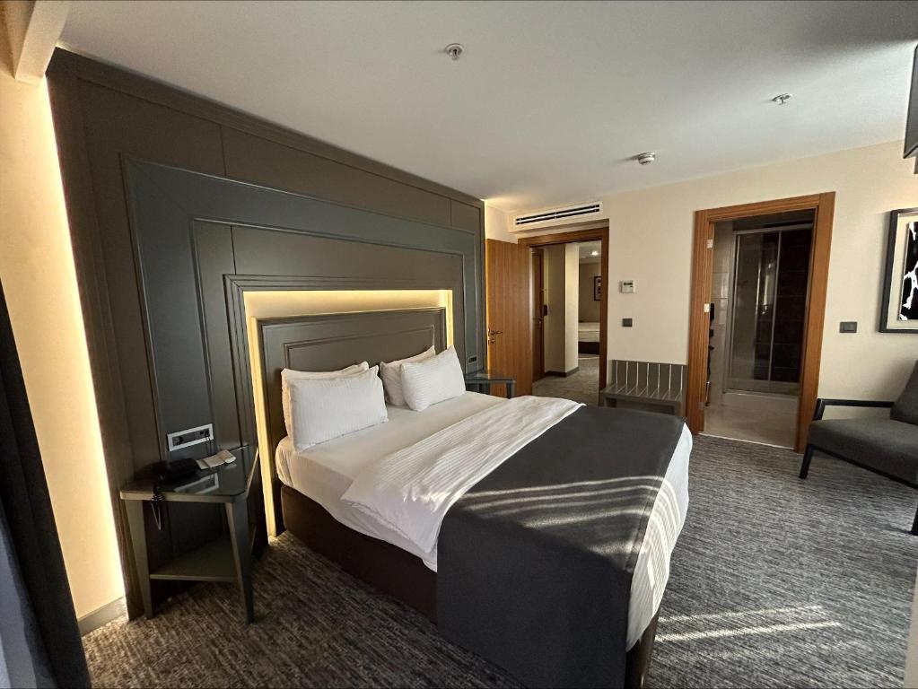伯萨Grand Turkuaz Hotel的一间卧室配有一张大床和一把椅子