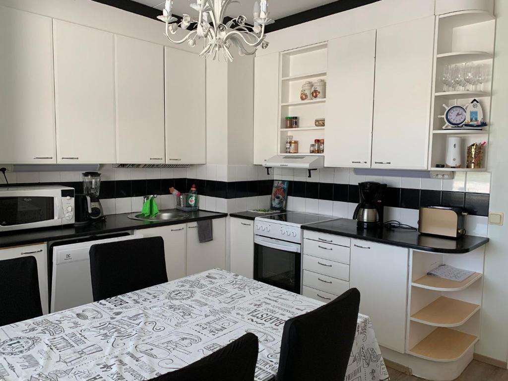 图尔库2 bedroom apartment, Turku的厨房配有白色橱柜、桌子和吊灯。