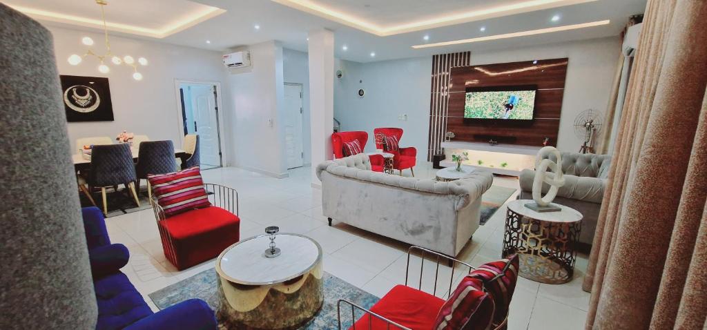 MaiyegunLuxury 3-Bed house in gated estate with pool Lekki的客厅配有红色和蓝色的椅子和电视