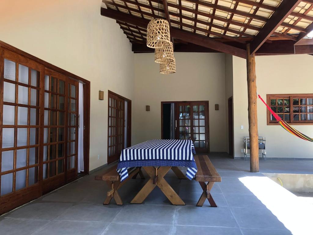 库穆鲁沙蒂巴Casa Morena Luz - espaço e conforto, perto da praia的一间带长凳、桌子和吊灯的房间