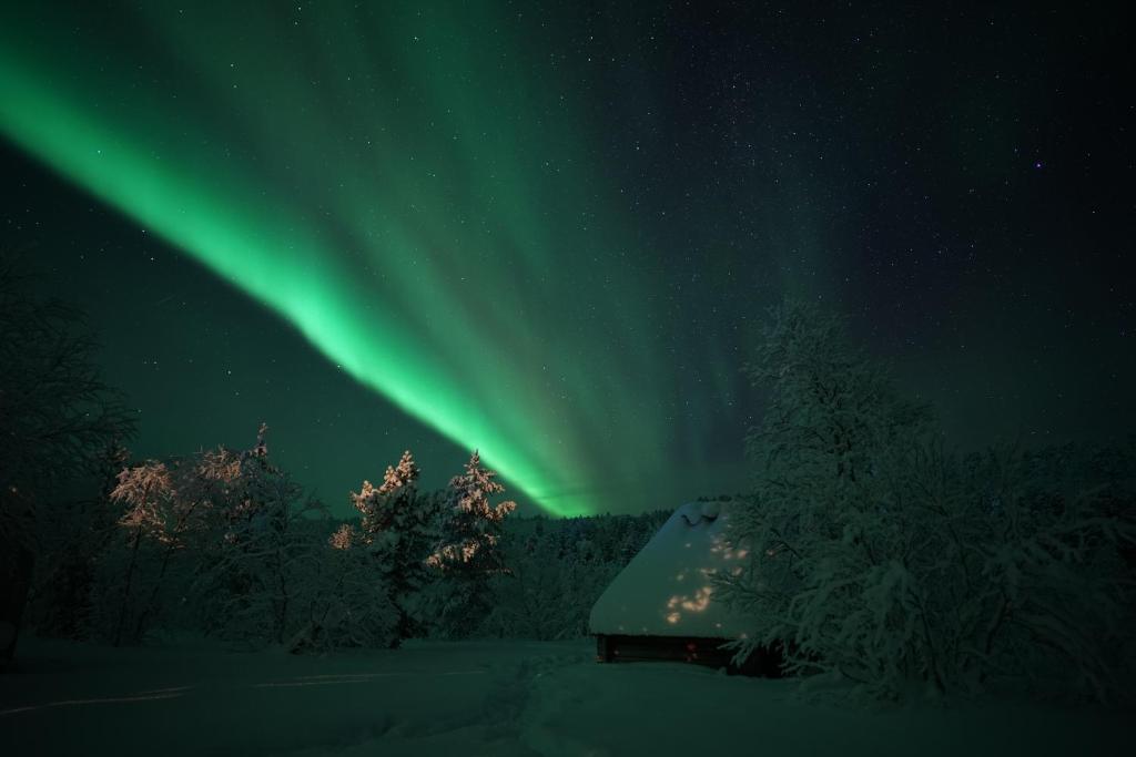 伊纳利Muotkan Ruoktu Tunturikyla的小屋上方的天空中闪烁着极光