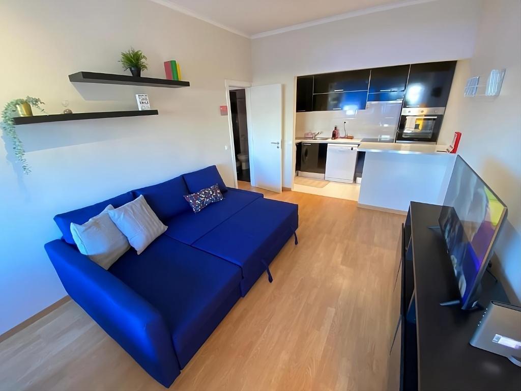 里斯本Columbano's House - Apartment in Central Lisbon的一间带蓝色沙发的客厅和一间厨房