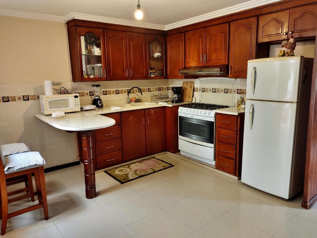昆卡Casa Quirola hermosa y muy grande的厨房配有木制橱柜和白色冰箱。