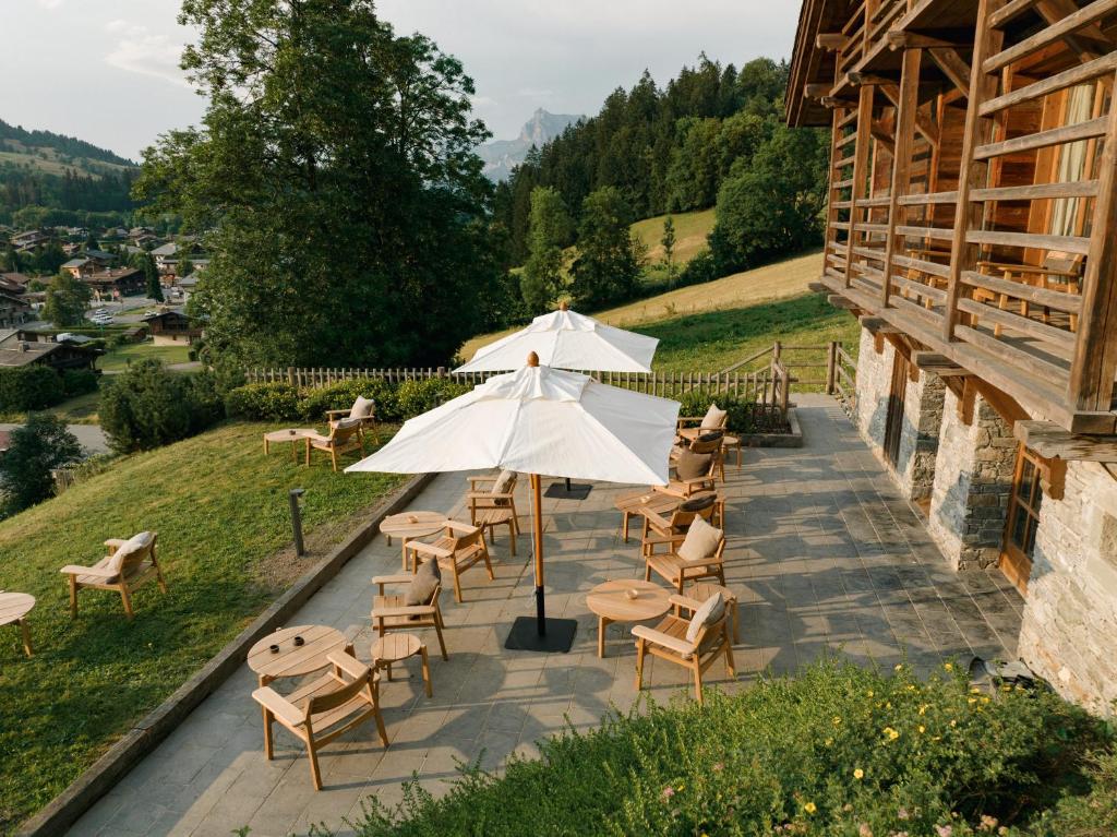 梅杰夫Zannier Hotels Le Chalet的一个带桌椅和遮阳伞的庭院