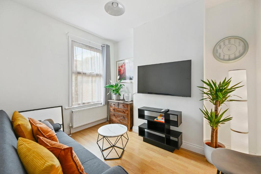 伦敦Cosy Urban Oasis 2 Bedroom Flat in Tottenham ( Sleeps 5 People )的客厅配有蓝色的沙发和平面电视。